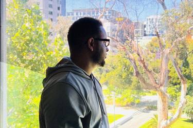Ismail Hussein, 30, a refugee from Somalia looks out from his room at the Park Hotel in Melbourne.