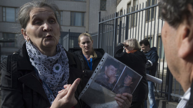 A woman with the Mothers of Srebrenica holds the photographs of two victims of the Bosnian war as she talks to the legal team for Radovan Karadzic, right, after the court upheld his conviction at The Hague, Netherlands.