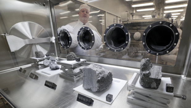 Ryan Zeigler, Apollo sample curator, left, stands next to a nitrogen-filled case displaying various lunar samples collected during Apollo missions 15, 16 and 17.