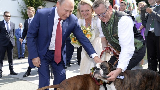 Russian President Vladimir Putin, left, pets dogs as he attends the wedding of Austrian Foreign Minister Karin Kneissl, centre, with with Austrian businessman Wolfgang Meilinger, right, in Gamlitz.