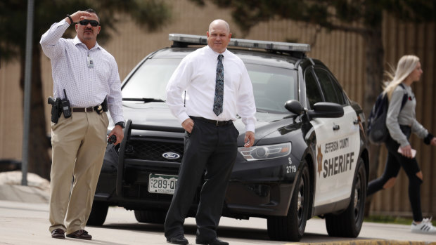 Columbine High School principal Scott Christy, right, watches as students leave the school on Tuesday.