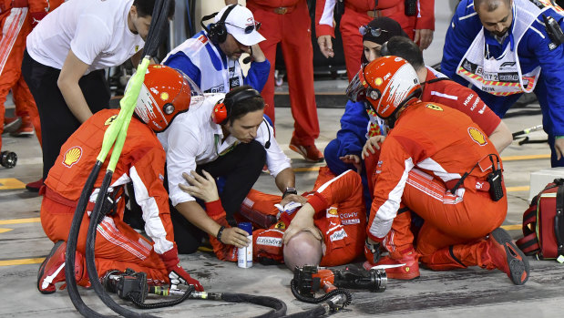 A Ferrari mechanic receives aid after being hurt during a pit-lane stop by Kimi Raikkonen.