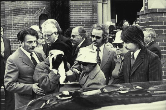 "Mrs. Clare Regan, her face covered, is helped today at the funeral of her murdered gangster son, John Stewart Regan, at St. Brigid's Church, Coogee. September 30, 1974."