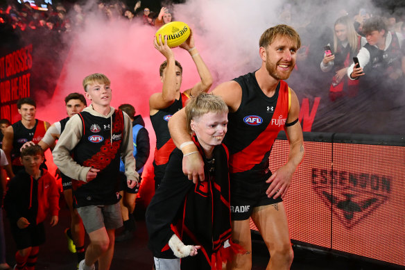 Dyson Heppell of the Bombers walks up the race with Harrison Pennicott. Harrison is 12 years old and was diagnosed with Scleroderma in 2016.