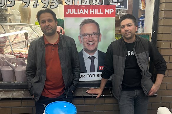 Dandenong community leader Aman Ullah Najimi (left) standing next to a sign for Julian Hill at the Ramadan night market.