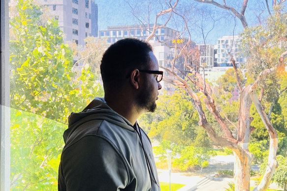 Ismail Hussein, 30, a refugee from Somalia looks out from his room at the Park Hotel in Melbourne.