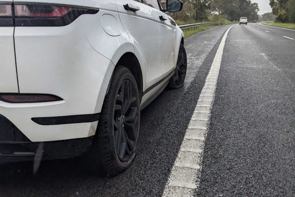 A car with two blown tyres on the side of the Hume Freeway.