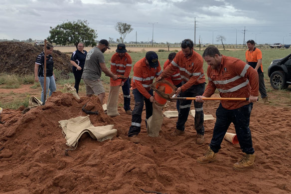 Construction workers quit work early today to help fill bags up with sand. 