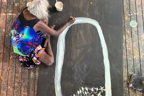 Mulkun Wirrpanda painting Pardalotes with earth pigment on board at Buku-Larrŋgay Mulka Centre, Northern Territory.
  