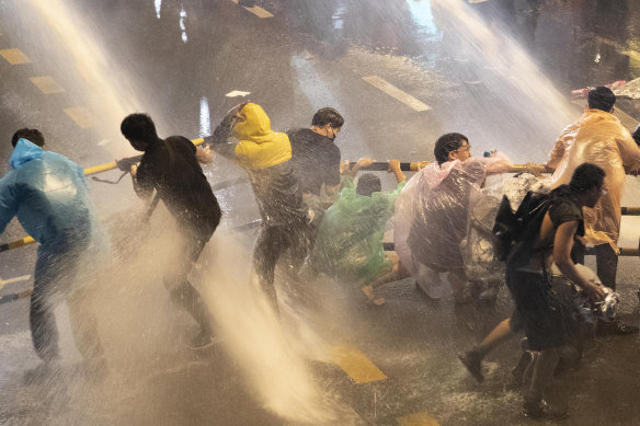 Protesters are hit with water canons as police try to clear an area in Bangkok on Friday.