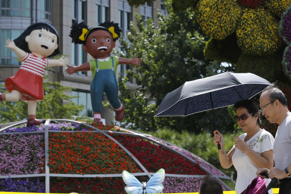 A couple and a child walk by a decoration titled \"Common Prosperity\" set up for the Forum on China-Africa Cooperation in Beijing.
