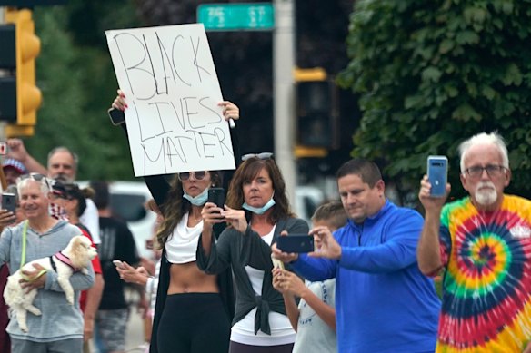People line up to watch as the motorcade with President Donald Trump passes in Kenosha, Wisconsin.