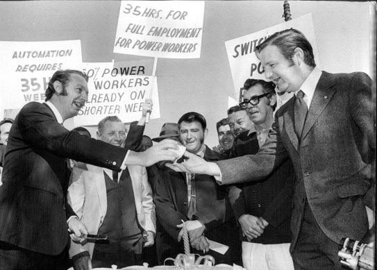 A cake to celebrate the union campaign for a 35-hour week. John MacBean, Labor Council industrial officer (front left) cuts the cake and hands a piece to Barry Unsworth, Labor Council organiser (front right), 1972.