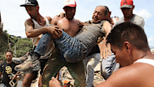 Neighbours carry a man rescued from the rubble of a collapsed building after earthquakes struck La Guaira, Venezuela,