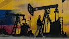A local walks past a mural featuring oil pumps and wells in Caracas, Venezuela, this week. 
