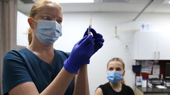 Nurse Mariia Kulchitska prepares a dose of flu vaccine for patient Bronte May-Horswood at the O’Connell Street Clinic in Sydney on Wednesday.