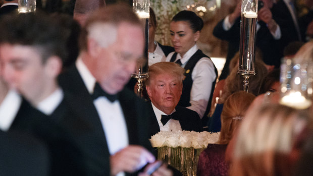 US President Donald Trump sits at his table during a New Year's Eve gala at his Mar-a-Lago resort Sunday.