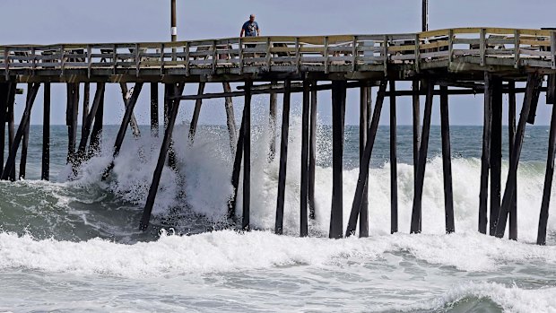 Waves crash under a pier in Kill Devil Hills, NC.