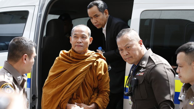 Thai Buddhist monk Phra Buddha Isara is escorted by Thai police officers at the Criminal Court in Bangkok.