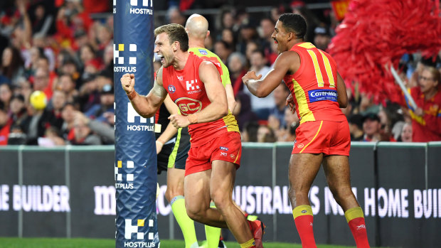 Big day out: Gold Coast's Sam Day (left) celebrates a goal against Essendon.