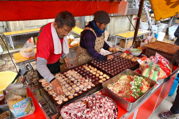 Vendors prepare takoyaki octopus balls stall at Kitano-Tenmangu Shrine. 