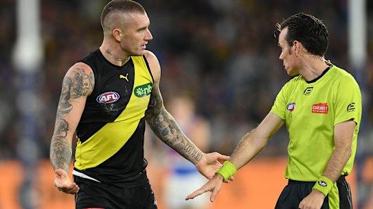 A wired-up umpire explains a decision to Dustin Martin.