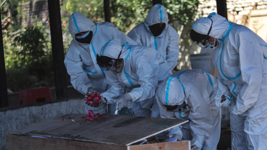 Family members put flowers as they perform the last rites for a COVID-19 victim at a crematorium in Jammu, India on Sunday.
