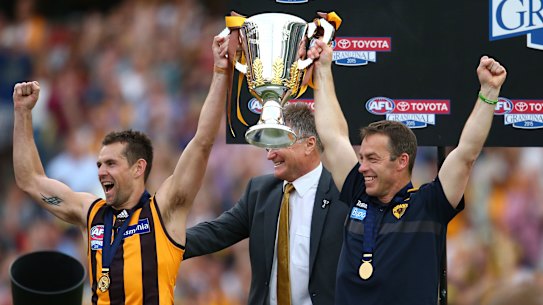 Clarkson and Hawthorn’s Luke Hodge hold the 2015 premiership cup. Clarkson coached the Hawks to four flags.