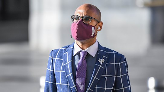 Man wearing a mask crossing the road outside Flinders street station. 