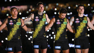 Richmond players stand for a minute’s silence under the lights of the MCG.
