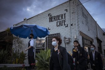 Taylor from The Herbert Cafe, Northcote, readies the venue for patrons as Santa Maria College students return to school.