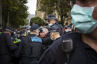 Police lead a man away after he clashed with protesters near Flinders Street Station on Tuesday.