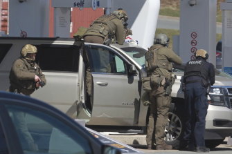 Royal Canadian Mounted Police officers prepare to take a suspect into custody at a gas station in Enfield, Nova Scotia on Sunday. 