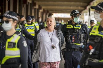 A woman is arrested at Queen Victoria Market on Saturday afternoon after an anti-vaccine protest. 