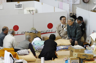 Akihito, in green, talks to evacuees after Fukushima in 2011.