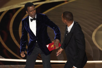 Chris Rock, left, reacts after being hit on stage by Will Smith while presenting the award for best documentary feature at the Oscars.