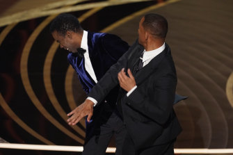 Will Smith, right, hits presenter Chris Rock on stage while presenting the award for best documentary feature at the Oscars.
