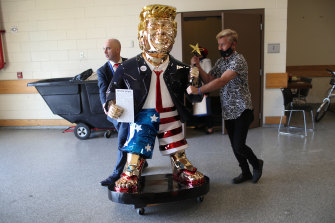 Tommy Zegan (right) wheels his statue of former President Donald Trump to a van during the Conservative Political Action Conference in February.
