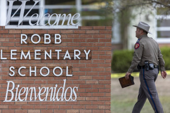 A state trooper walks past the Robb Elementary School sign in Uvalde, Texas.