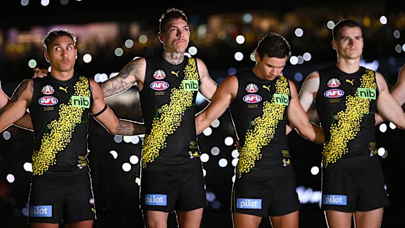 Richmond players stand for a minute’s silence under the lights of the MCG.