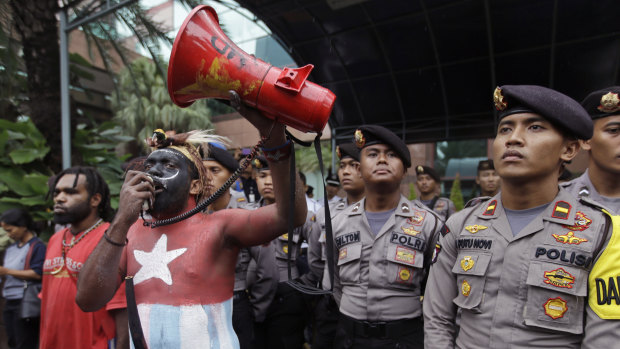 In this March 20, 2017, file photo, a Papuan activist whose body is painted in the colours of 'Morning Star' separatist flag shouts slogans as police officers stand guard during a protest in Jakarta, Indonesia.