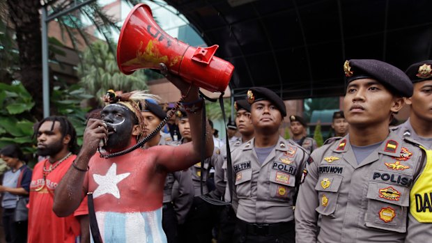 In this March 20, 2017, file photo, a Papuan activist whose body is painted in the colours of 'Morning Star' separatist flag shouts slogans as police officers stand guard during a protest in Jakarta, Indonesia.