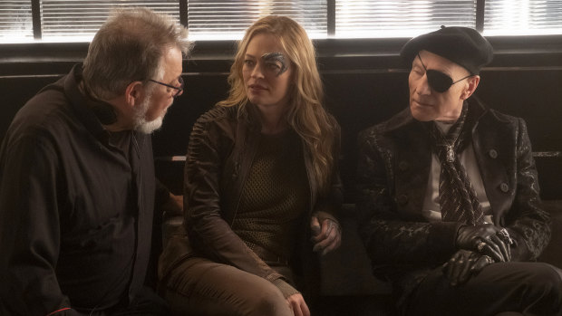Jonathan Frakes directing Star Trek: Picard, pictured discussing a scene with actors Jeri Ryan and Patrick Stewart.