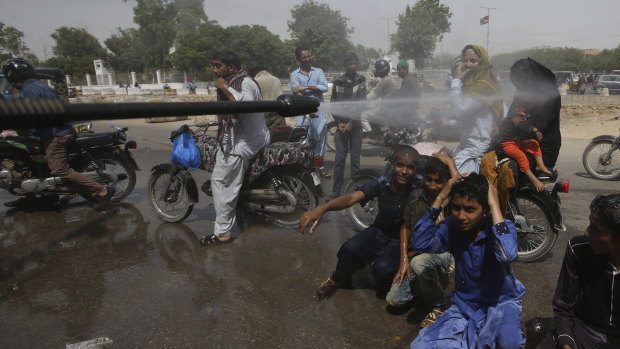 Pakistani volunteer spray water on people to keep them cool as temperatures reached 44 degrees in Karachi on Monday.