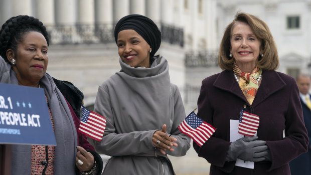 Ilhan Omar, centre, smiles as she stands between fellow Democrats Sheila Jackson Lee, left, and Speaker of the House Nancy Pelosi, outside the Capitol.
