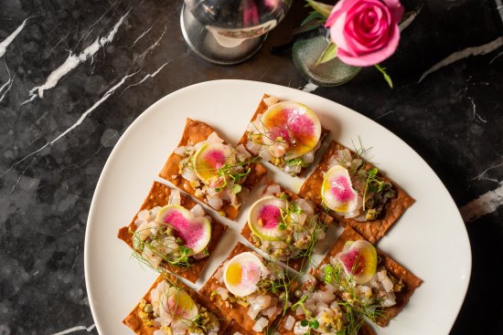 Kingfish crudo with olive purée, Sicilian capers and basil cress on flatbread.
