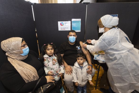 Osama Jabry receiving his COVID-19 vaccination from nurse Sonya El-Abbas, accompanied by his wife Manal Kareen, and children Rokaya and Hussien at Broadmeadows Town Hall vaccination hub.