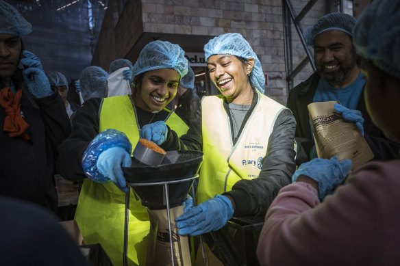 Volunteers Sochini Pryaratne and Nitusha Sathananthan help prepare a food package.