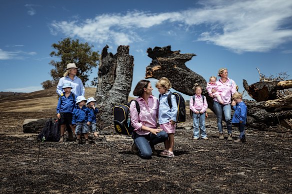 Annabelle Cleeland and her five-year-old daughter Quinn (c) with Lou Webb (l) and her children Tom and Fred, 3, and George, 6, and Felicity Jeffrey and her children Jemima,6, Sebastien,4 and Claudio,1, stand in the burnt-out Jeffrey property in Whiteheads Creek. 