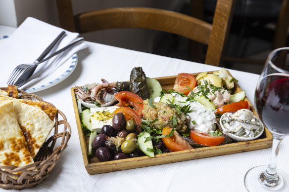 The appetiser selection includes melitzanosalata (eggplant dip), tarama and tzatziki, marinated calamari and artichokes, dolmades, a slab of feta and vinegared anchovies.